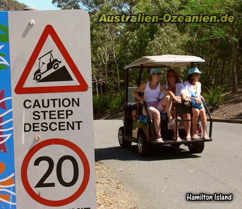 Golfbuggy mit Passagieren und Straßenschild
